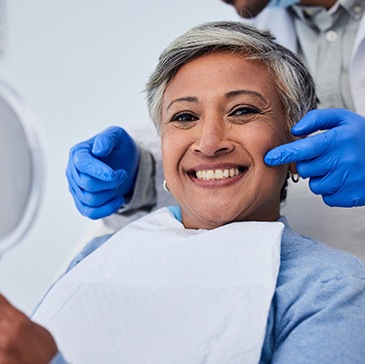 Woman smiling while holding handheld mirror