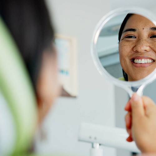 Woman smiling at reflection in dentist office